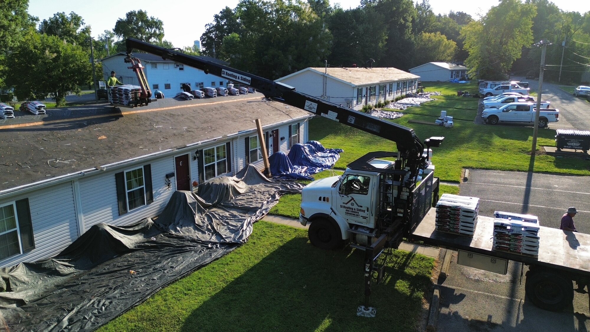 Aerial view of a roofing crew working across a long residential building