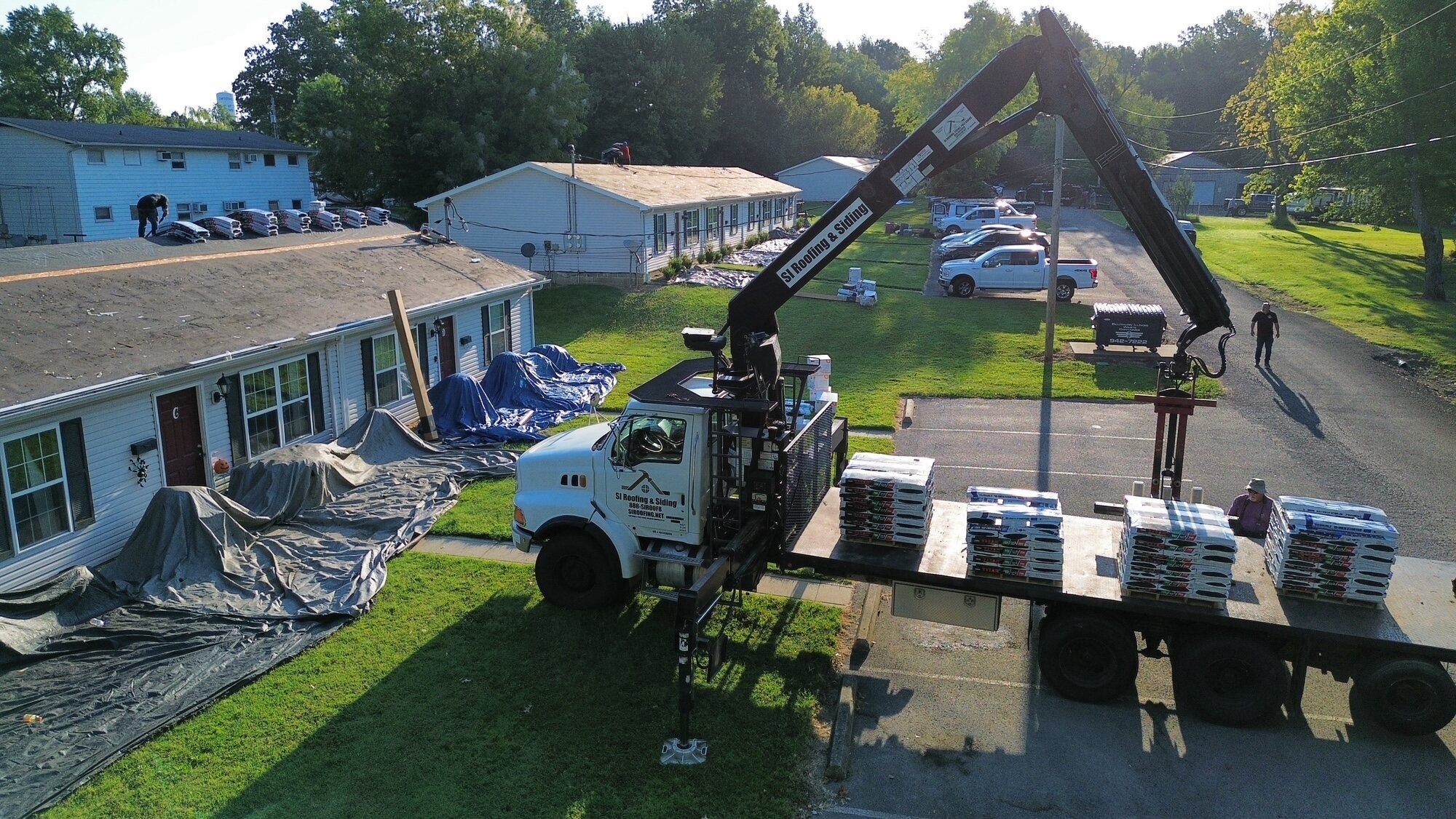 Roofing materials being delivered beside an active roof replacement